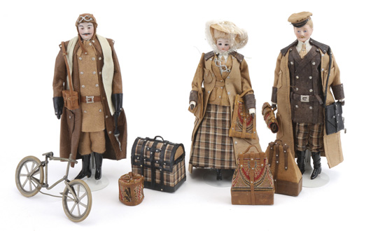 Trio of dolls in fashionable travel attire, accompanied by luggage, satchels and a bicycle attributed to Carette, $9,775. Noel Barrett Auctions image.